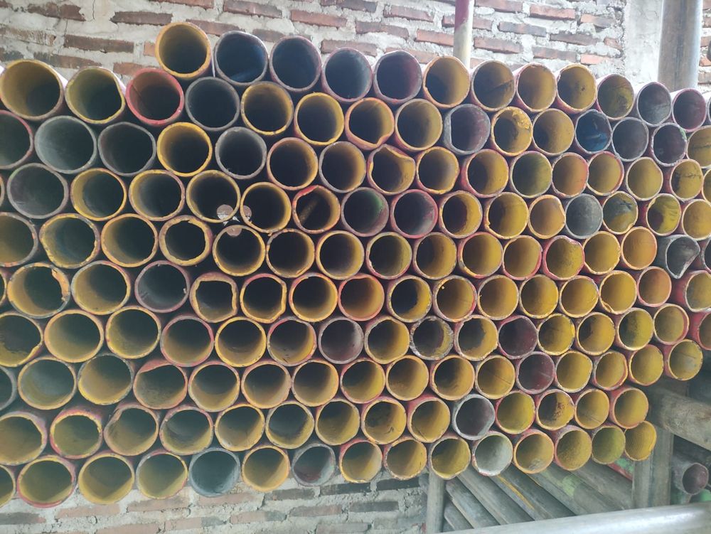 Tumpukan pipa scaffolding kuning di gudang
